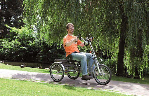 Ein Man fährt ein e-Dreirad mit Handkurbeln