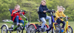 Drei Kinder fahren auf ihren Dreirädern