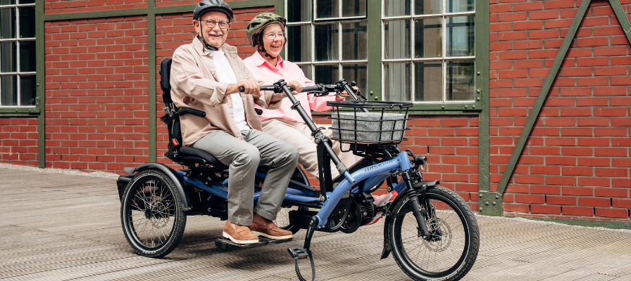 Ein Mann und eine Frau sitzen vor einer Backsteinwand auf dem Hase Bikes Kettwiesel Two